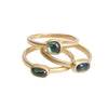 Three gold rings with green gemstones on a white background