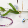 Necklace with a flower pendant on a white background with green leaves and flowers.