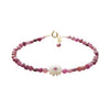 Pink roby beaded bracelet with a white flower charm on a white background