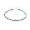 Turquoise beaded bracelet with gold accents on a white background