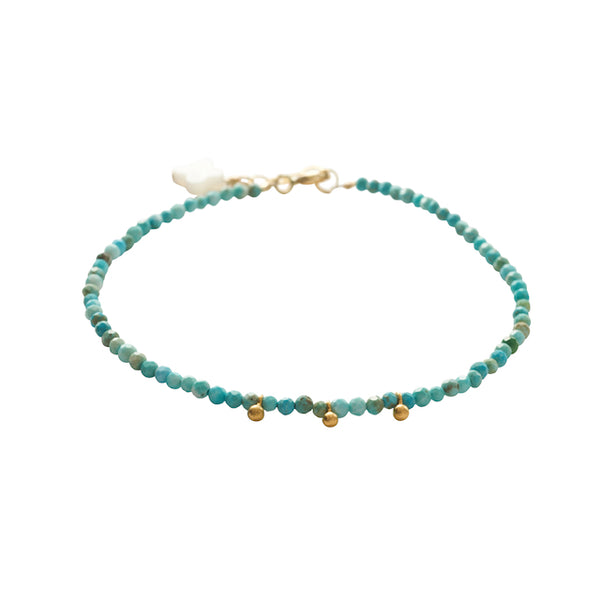 Turquoise beaded bracelet with gold accents on a white background