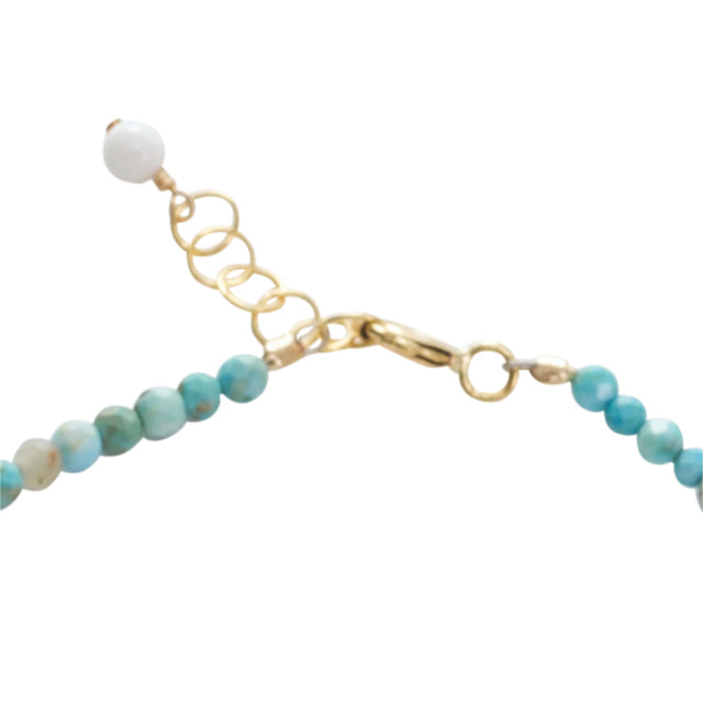 Bracelet with turquoise beads and gold chain on a white background