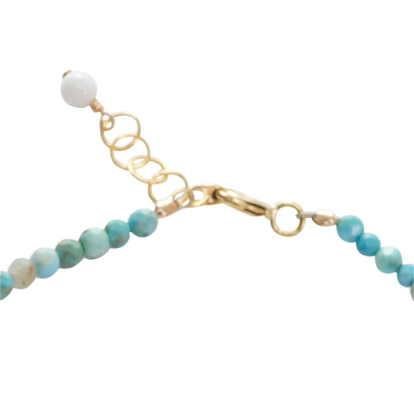 Bracelet with turquoise beads and gold chain on a white background