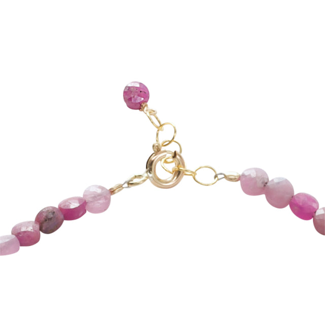 Bracelet with pink beads and gold clasp on a white background
