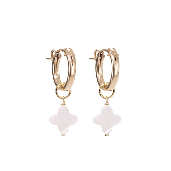 Gold hoop earrings with white flower-shaped charms on a white background